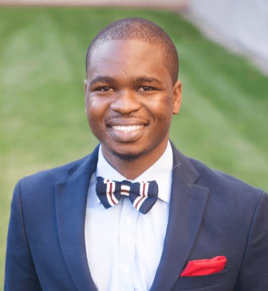 Adedotun Ogunbajo, PhD, MPH, wear a navy suit with a bowtie and red pocket square